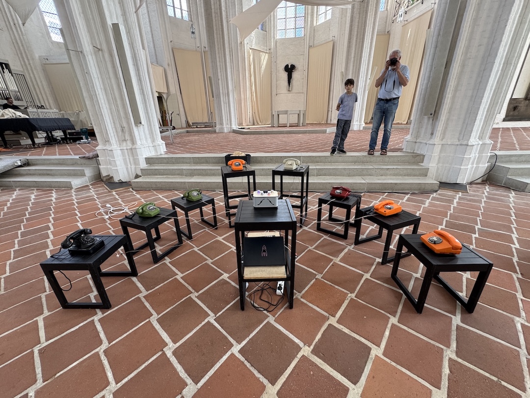 8 Telefone auf Hockern in einer Kirche